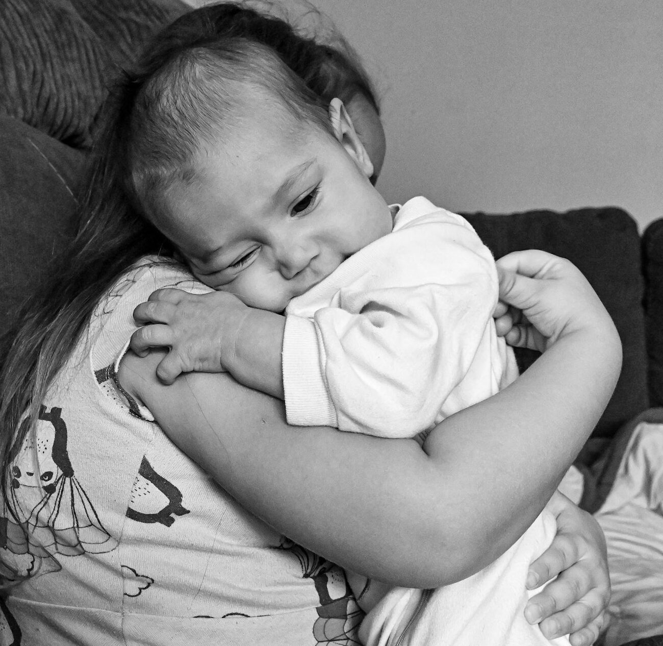 newborn baby and sibling hugging